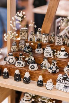 there are many small black and white vases on the shelf in front of each other