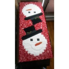 a red and white snowman quilted on top of a wooden table next to a window