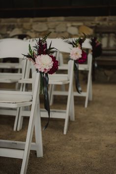 the chairs are decorated with flowers and ribbons for an outdoor wedding ceremony at stone barn