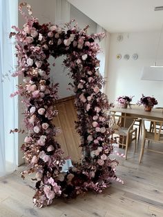 a mirror that has flowers on it in the middle of a room next to a table