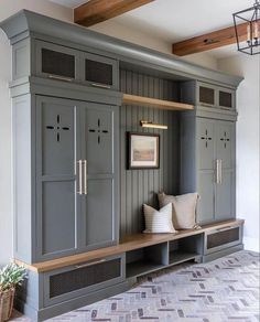 a room that has some gray cabinets and pillows on the bench in front of it