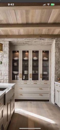 an image of a kitchen setting with white cabinets and marble counter tops, along with wood flooring