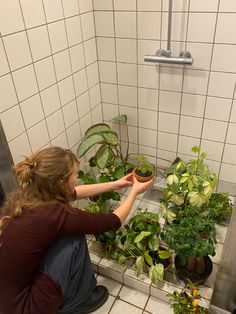 a woman kneeling down in front of some plants