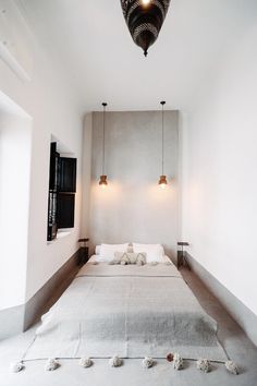 a large bed sitting in the middle of a bedroom next to two lamps hanging from the ceiling