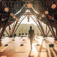 a woman is walking in the middle of a room with lots of yoga mats on it