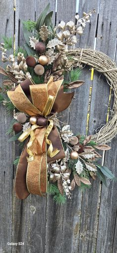 a wreath is hanging on the side of a wooden fence with pine cones and other decorations