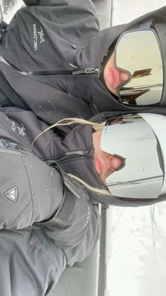 a man is sitting in the snow with his reflection in a side view car mirror