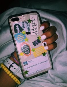 a woman's hand holding an iphone case with stickers and stars on it