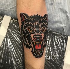 a man's arm with a wolf tattoo on it and an orange eyed eye