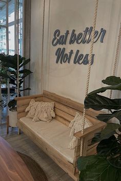 a wooden swing hanging from the side of a wall next to a potted plant