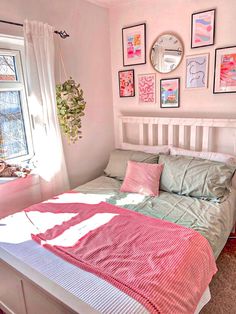 a bedroom with pink and green bedding and pictures on the wall over the bed