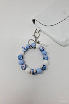 a blue and white beaded bracelet with a silver charm on it next to a purse