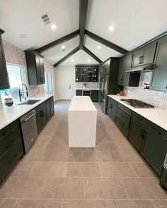 a large kitchen with black cabinets and white counter tops, along with an island in the middle