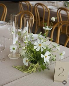 the table is set with white flowers, candles and place cards for guests to sit at