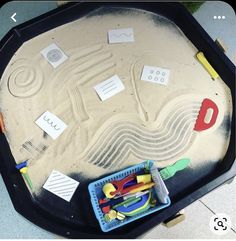 a sand tray with toys on it and writing on the top in front of it