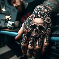 a tattooed hand with a skull and flowers on it