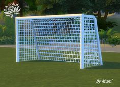 a soccer goal in the middle of a grassy area with trees and bushes behind it