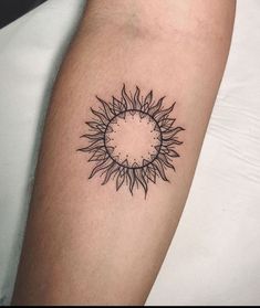 a black and white photo of a sunflower tattoo on the left arm, with an outline in the middle