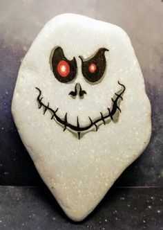 a close up of a rock with a face painted on it's side and red eyes