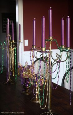 purple and green beaded candelabra with candles on them sitting on a table