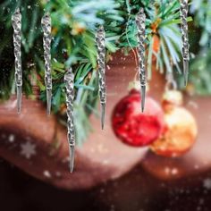 a christmas ornament hanging from a tree with icicles on it and a bauble in the foreground