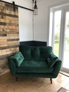 a green couch sitting on top of a hard wood floor next to a sliding glass door