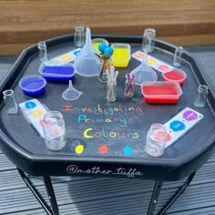 a black table topped with lots of different colored liquids and flasks on top of it