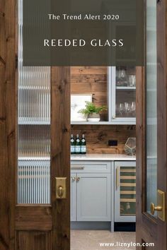 an open door leading to a kitchen with wood paneling and glass doors on both sides