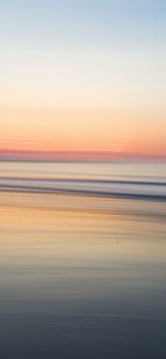 two surfers walking on the beach at sunset