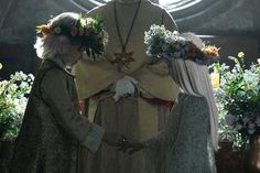 two women standing next to each other in front of a statue with flowers on it