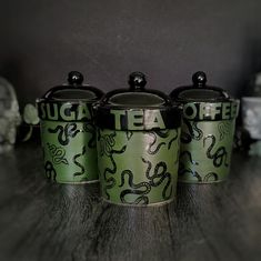 three green canisters sitting on top of a wooden table