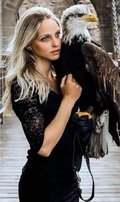 a woman holding an eagle in her hands