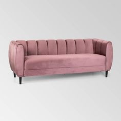 a pink velvet sofa with black legs and arm rests on an isolated white background,