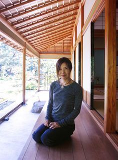 a woman sitting on the floor in front of a wooden building with windows and doors