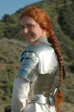 a woman with red hair wearing a silver armor