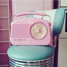 a pink and blue radio sitting on top of a stack of stacked metal pans