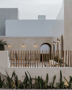 a white house with wooden slats on the front and side walls, surrounded by plants