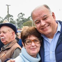 an older man and woman taking a selfie in front of a group of people