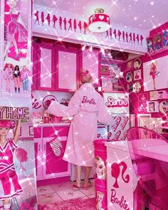 a woman standing in front of a barbie doll house kitchen with pink furniture and accessories