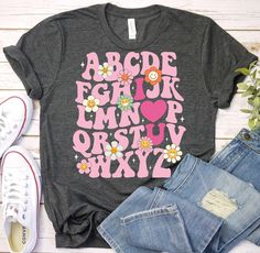 a t - shirt with the words abcdg and flowers on it next to some jeans