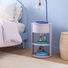 a bedroom with blue walls and a white round shelf next to a lamp on the nightstand