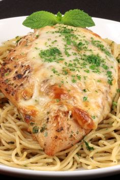 a white plate topped with pasta and meat covered in sauce, garnished with parsley