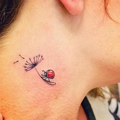 a ladybug tattoo on the back of a woman's neck