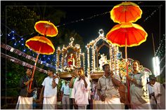 some people are standing around with umbrellas and lights in the background at an outdoor event