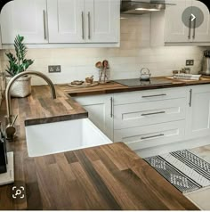 a kitchen with white cabinets and wood counter tops