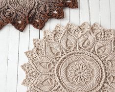 two crocheted doily sitting on top of a white wooden floor next to each other