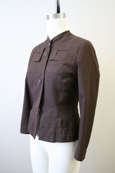 "Description: 1940s brown wool jacket, with an amazing geometric appliqued design. Button front with long sleeves. It has a hook and eye closure at the top button. Shaped, nipped waist with padded shoulders. Fully lined. Condition: In fair condition, with no stains. It has scattered moth holes over the body, sleeves, and cuffs (see the photos). It is missing two front buttons, although the buttons are very simple and would be fairly easy to replace. Designer: Adrian Stated Size: n/a Measurements Vintage Stand Collar Blazer For Work, Vintage Blazer With Stand Collar For Work, Fitted Wool Blazer With Snap Buttons, Brown Outerwear With Covered Buttons For Work, Brown Stand Collar Blazer With Buttons, Brown Retro Blazer For Work, Vintage Brown Blazer For Office, Brown Single Breasted Blazer With Stand Collar, Formal Brown Stand Collar Blazer