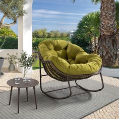 a green chair sitting on top of a rug next to a table and potted plant