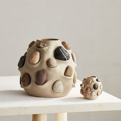 there is a vase with rocks on it next to a small rock pot that has been placed on a table