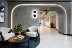 a living room with two chairs and a coffee table in front of a wall that has lights on it